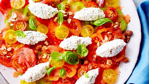 Tomatensalat mit Frischkäsenocken und frischem Basilikum auf einem großen Servierteller - Foto: House of Food / Bauer Food Experts KG