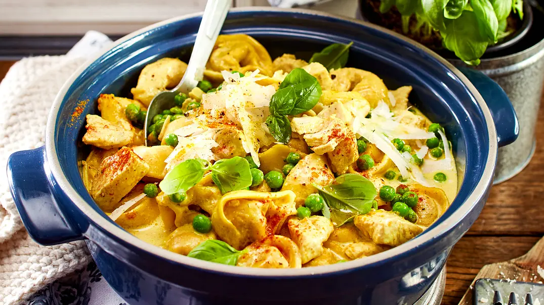 Tortellini mit cremiger Soße und Erbsen in einem blauen Topf mit Löffel - Foto: LECKER @ Bauer Media Group Tortellini mit cremiger Soße und Erbsen in einem blauen Topf mit Löffel - Foto: LECKER @ Bauer Media Group