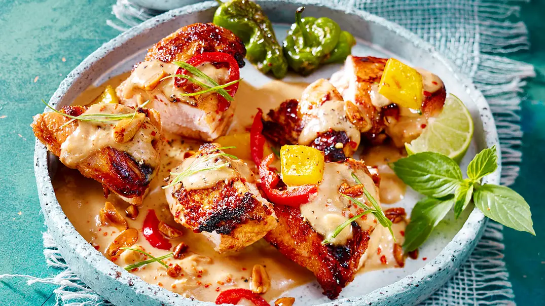Hähnchen in Erdnusssoße mit grüner, gelber und roter Paprika in einem tiefen grauen Teller. - Foto: LECKER @ Bauer Media Group Hähnchen in Erdnusssoße mit grüner, gelber und roter Paprika in einem tiefen grauen Teller. - Foto: LECKER @ Bauer Media Group