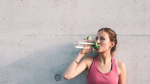 Sportliche Frau trinkt aus Trinkflasche - Foto: iStock / golero