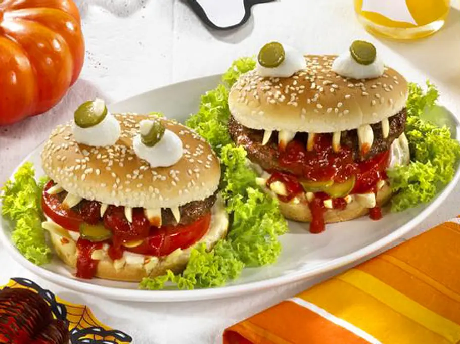 Vampi-Burger für Halloween Rezept Zwei Vampir-Burger auf Salat mit Zähnen aus Käse, „blutiger“ Tomatensoße und Augen aus Mozzarella und Gurkenscheiben.