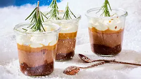 Drei kleine Weckgläser gefüllt mit Schichten aus Cheesecake und Sahnehaube mit kleinem Tannenzwei als Deko, rundherum Deko-Schnee - Foto: LECKER @ Bauer Media Group