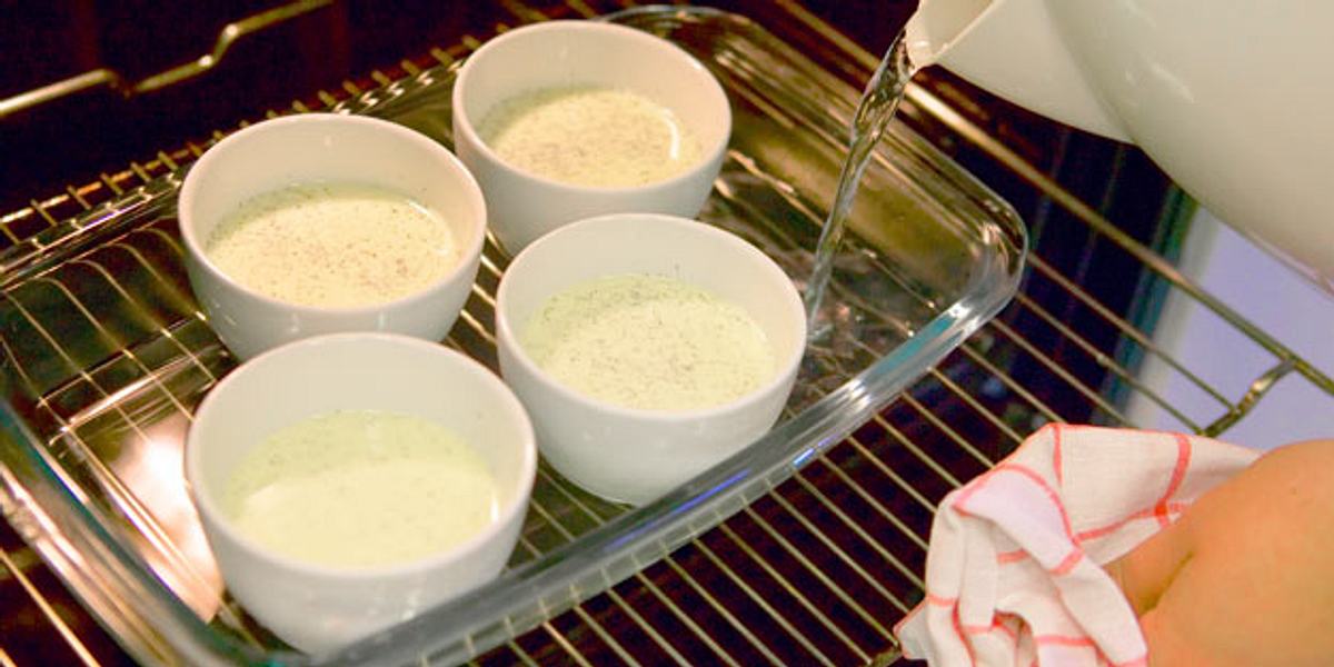 Die Vanille-Ei-Sahne-Mischung für Crème brûlée stockt im Backofen in einem heißen Wasserbad.