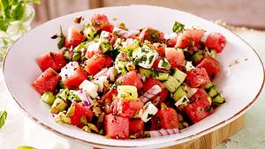 Wassermelonensalat mit Gurke, Feta, Kräutern und gehackten Pistazien in einer weißen Schüssel. - Foto: House of Food / Bauer Food Experts KG