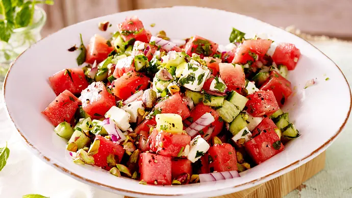 Wassermelonensalat mit Gurke, Feta, Kräutern und gehackten Pistazien in einer weißen Schüssel. - Foto: LECKER @ Bauer Media Group Wassermelonensalat mit Gurke, Feta, Kräutern und gehackten Pistazien in einer weißen Schüssel. - Foto: LECKER @ Bauer Media Group