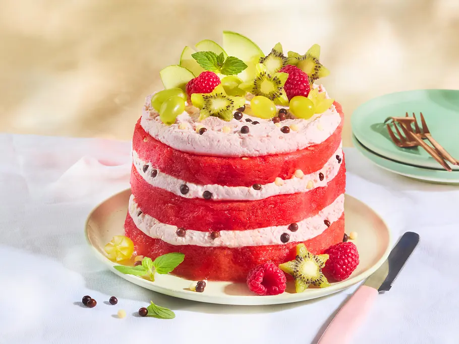 Einfacher geht's nicht! Wassermelonen-Torte ohne backen Wassermelonenschichttorte mit Mascarpone-Himbeercreme. Darauf Obst: Helle Weintrauben, Kiwis in Sternform, Himbeeren.