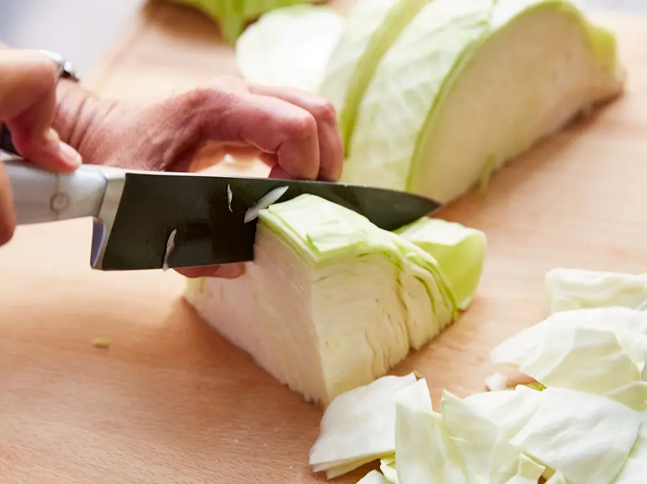 Weißkohl schneiden Mit einem Messer wird ein Viertel vom Weißkohl abgeschnitten