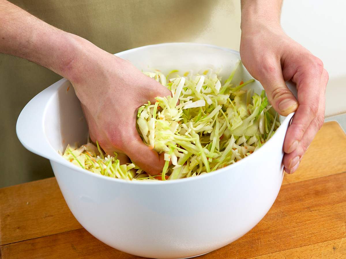 Für Coleslaw Weißkohl mit den Händen durchkneten