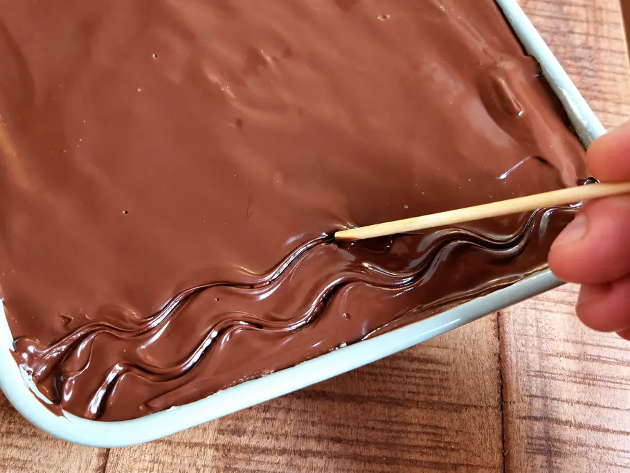 Donauwellen-Tiramisu verzieren. Mit einem Holzspieß wird das typische Wellenmuster auf des Donauwellen-Tiramisu gebracht.