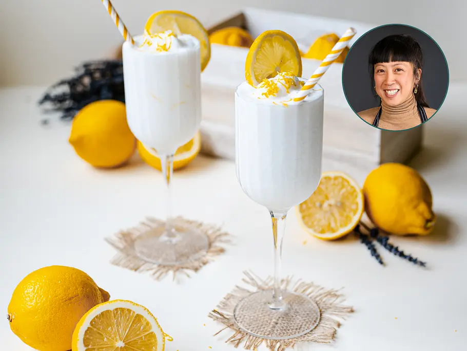 Weiße Whipped Frozen Lemonade in zwei Weingläsern, dekoriert mit Zitronenscheiben, Zitronenabrieb und gelb-weiß geringelten Trinkhalmen. Mit im Bild Redakteurin Nu.