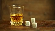 Whisky-Steine und gefülltes Whisky-Glas auf Holztisch - Foto: iStock/JurgaR