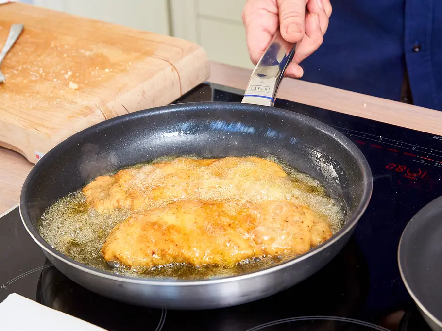 Schnitzel werden in einer Pfanne goldgelb gebraten.