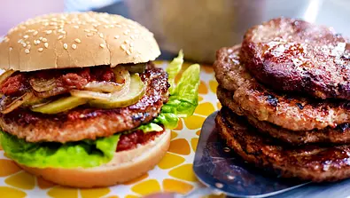 Ein dick belegter Hamburger mit Beef-Patty, Salat, Gurken und Zwiebeln - Foto: LECKER @ Bauer Media Group