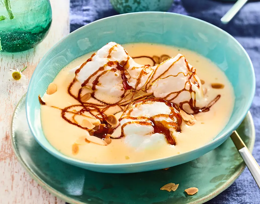 Zarte Schnee-Nockerln auf Vanillesoße mit Mandelblättchen und Karamellsoße.