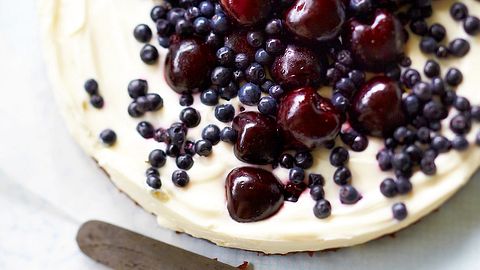 Ziegenfrischkäsetorte mit Süßkirschen und Blaubeeren, seitlich liegt ein Kuchenmesser - Foto: House of Food / Bauer Food Experts KG