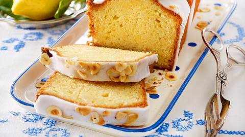 Zitronenkuchen aus der Kastenform mit Zuckerguss und einer Deko aus Haselnussblättchen - Foto: House of Food / Bauer Food Experts KG