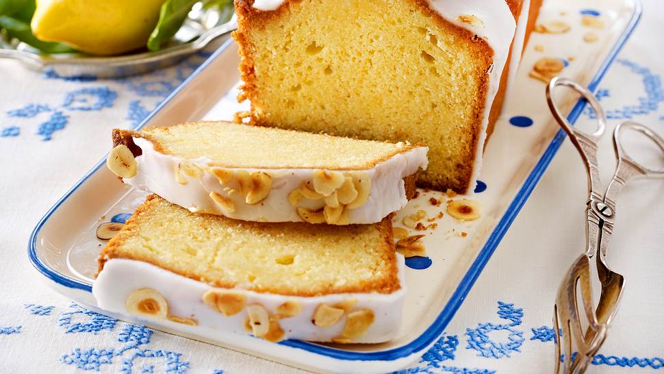 Zitronenkuchen aus der Kastenform mit Zuckerguss und einer Deko aus Haselnussblättchen - Foto: House of Food / Bauer Food Experts KG