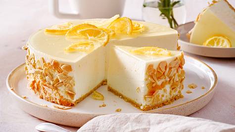 Hohe Zitronentorte ohne Backen aus Frischkäse, mit Eiswaffelboden und Zitronenscheiben-Dekoration auf einem hellen Teller mit kleinem Rand. - Foto: House of Food / Bauer Food Experts KG