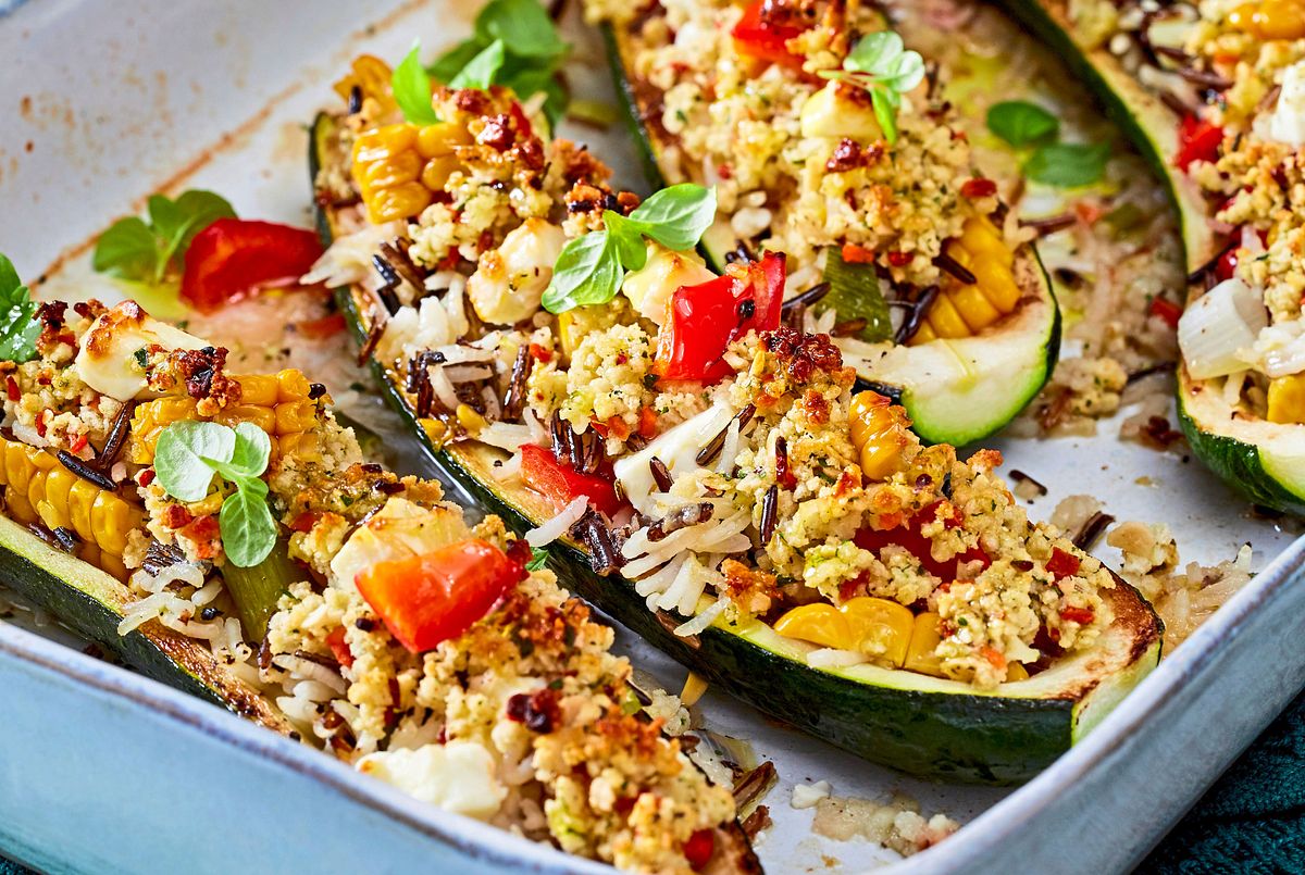 Gefüllte Zucchinihälften mit Reis, Paprika und Feta aus dem Ofen, serviert in einer Auflaufform.