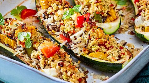 Gefüllte Zucchinihälften mit Reis, Paprika und Feta aus dem Ofen, serviert in einer Auflaufform. - Foto: House of Food / Bauer Food Experts KG