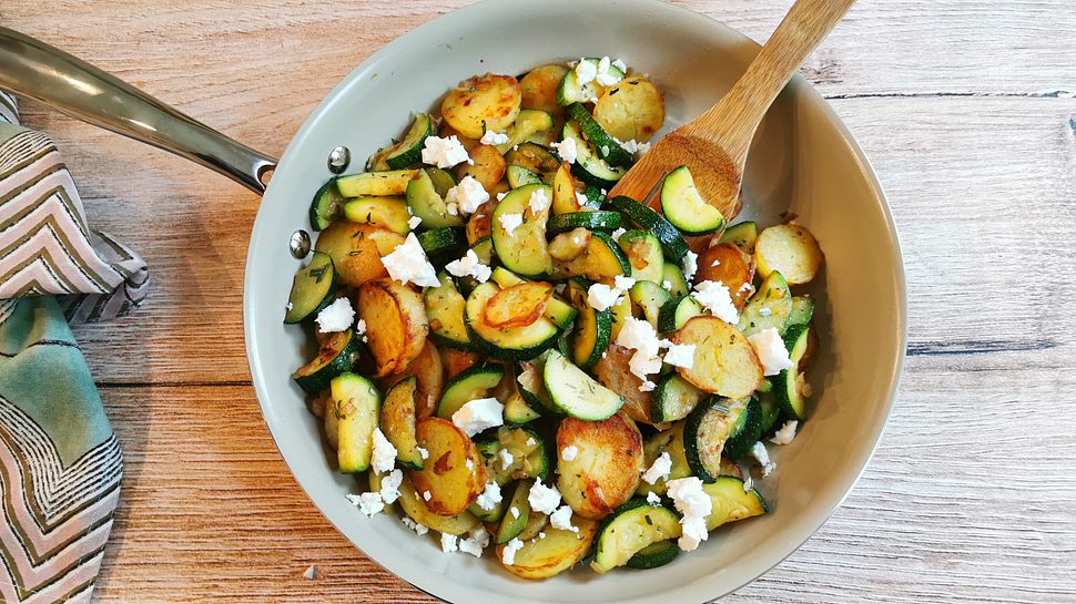 Zucchini-Kartoffel-Pfanne mit Feta bestreut auf einem Holztisch serviert. - Foto: LECKER @ Bauer Media Group / Birte Wloka