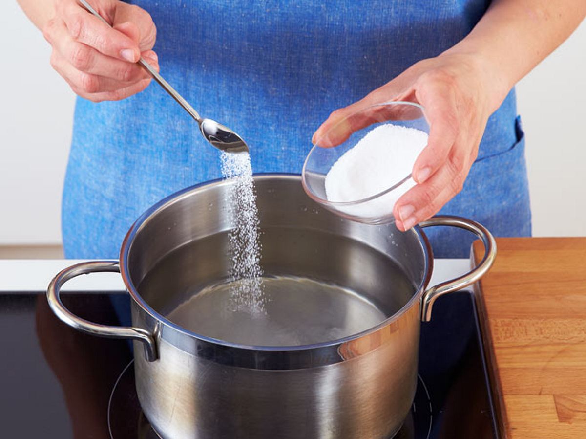 Zucker in einen Topf mit Wasser geben