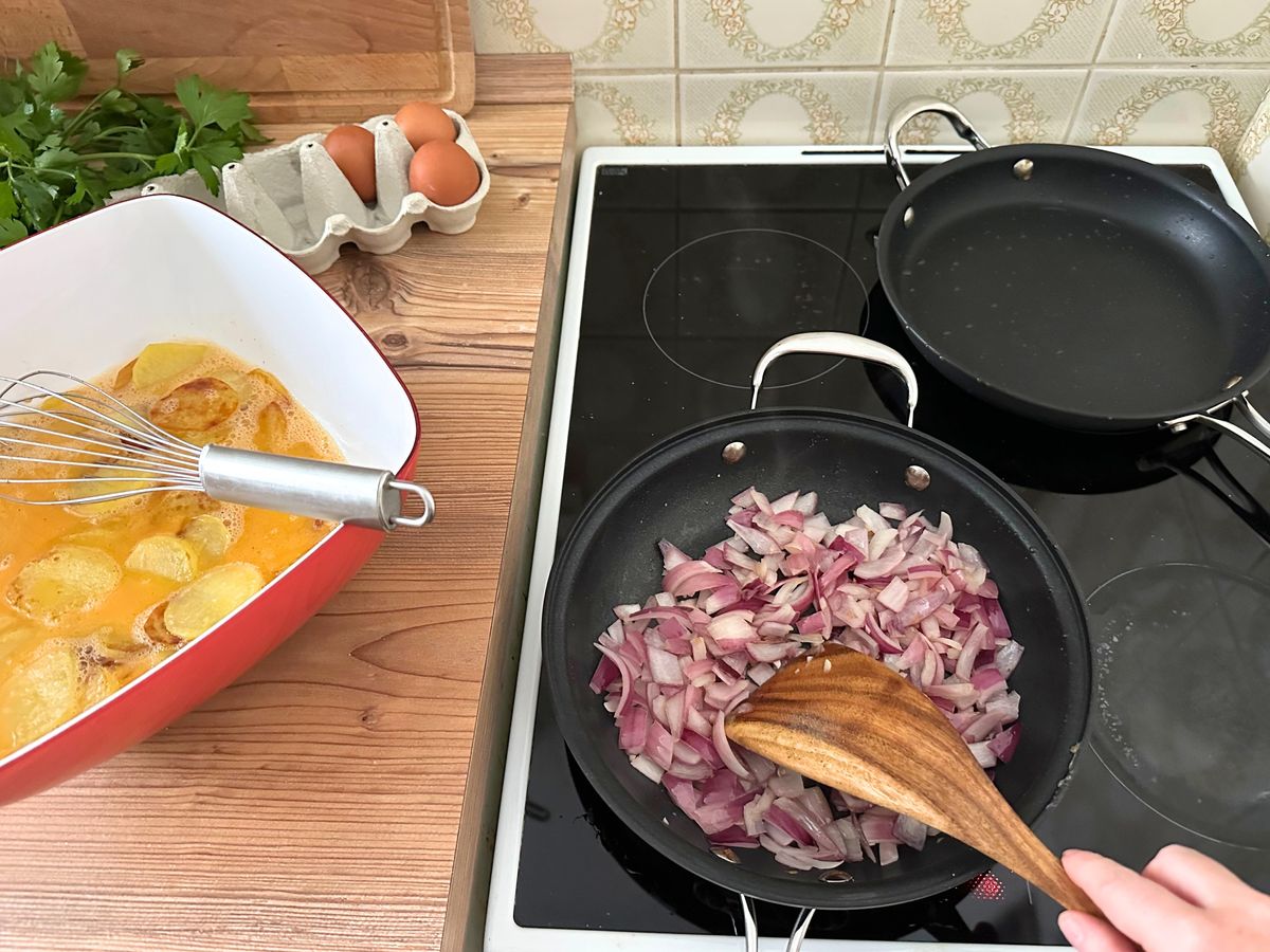 Rote Zwiebelspalten werden in der Hagen-Grote-Einzelpfanne auf dem Herd glasig gebraten