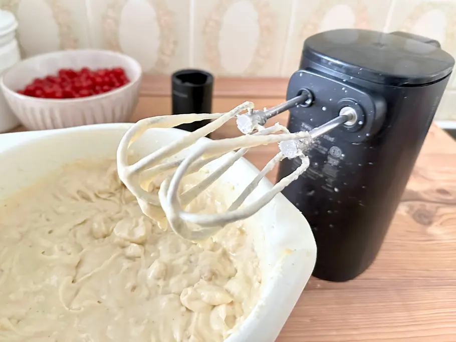 Neben einer Schüssel mit Rührteig steht der Zwilling Xtend Akku-Handmixer mit eingesetzten Quirlen, die so kurz sind, dass der Mixer an der Unterseite mit Teig bespritzt ist.