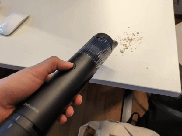 Krümel auf einem Schreibtisch werden mit dem Zwilling Xtend Handstaubsauger entfernt.